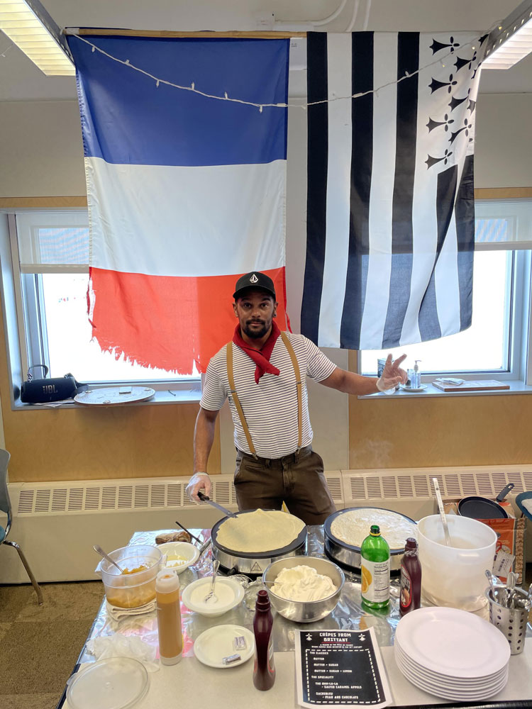Celas standing at a table filled with supplies for making crepes.