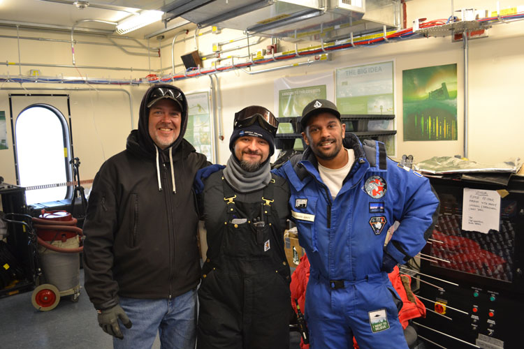 Three winterovers posing for camera in the IceCube Lab at the South Pole.