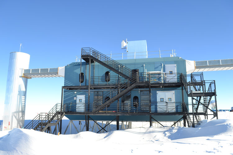 The IceCube Lab with accumulated snow around its base on a clear day.