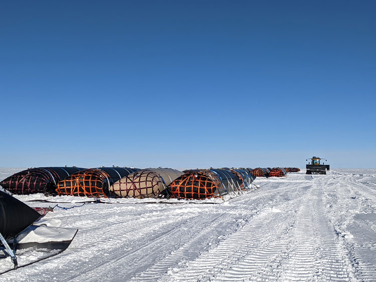 End view of long rows of fuel bladders out on the ice at the South Pole.