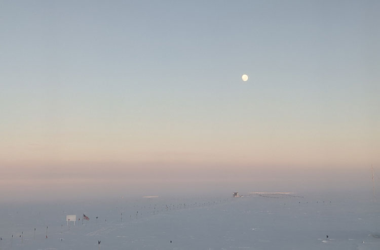 Rising moon high in the sky at the South Pole during sunset.