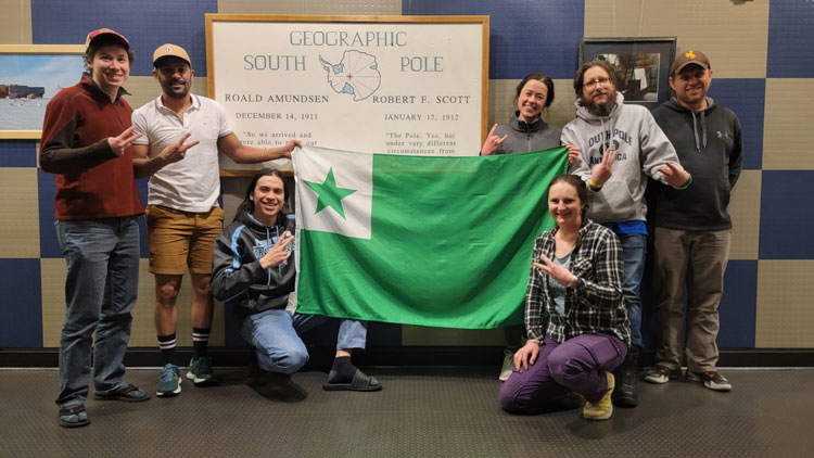 Group photo of South Pole Esperanto club holding up an Esperanto flag.