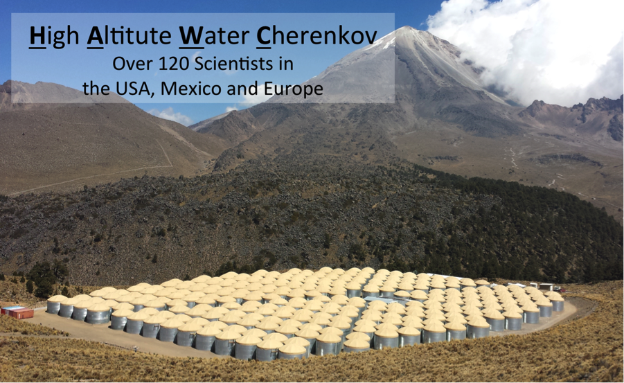 The HAWC gamma-ray observatory.  The picture shows 300 water Cherenkov detectors, covering an area of four football fields, and in the middle of the array, the electronics building. In the background is Pico de Orizaba, the tallest mountain in Mexico.