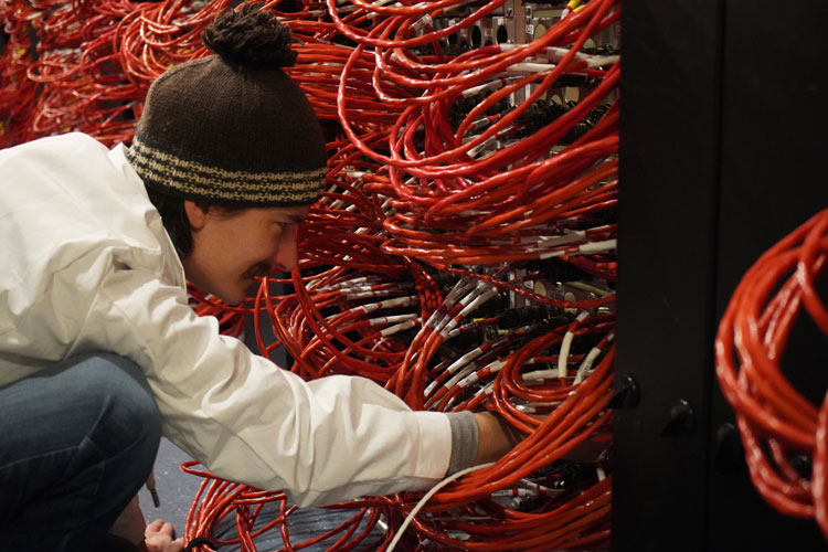 Close-up, side view of person working among mass of computer cables