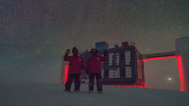 Winterovers outside waving in front of IceCube Lab at South Pole
