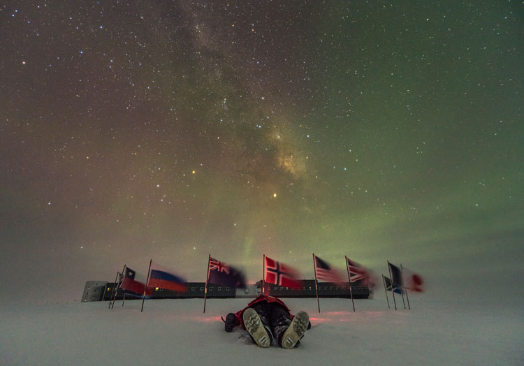 Lying down on snow under starry skies, with South Pole flags