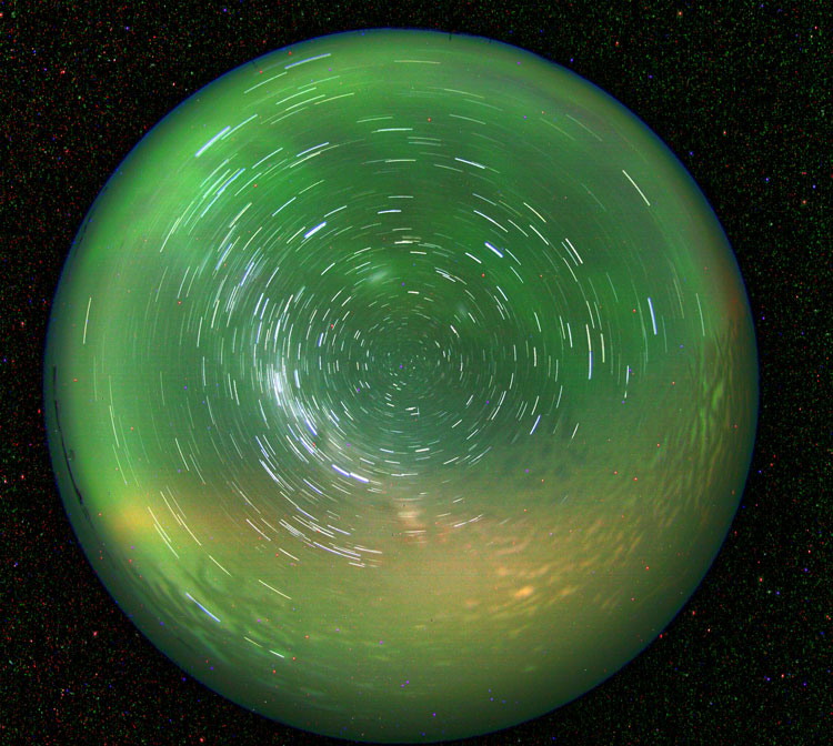 30-second exposure taken through a ceiling dome, a green sky with patterns of white lines.