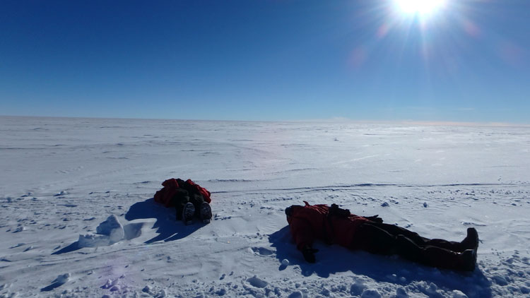 two bodies lying on the ice, sunbathing at the South Pole