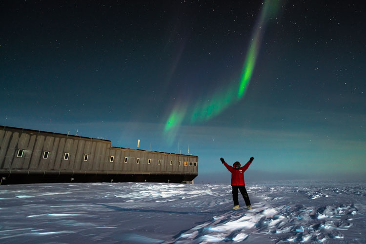 Aurora at South Pole, with person with arms in air