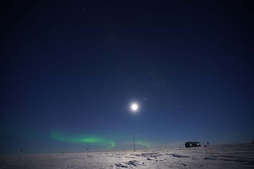 Auroras along horizon under bright moon at South Pole