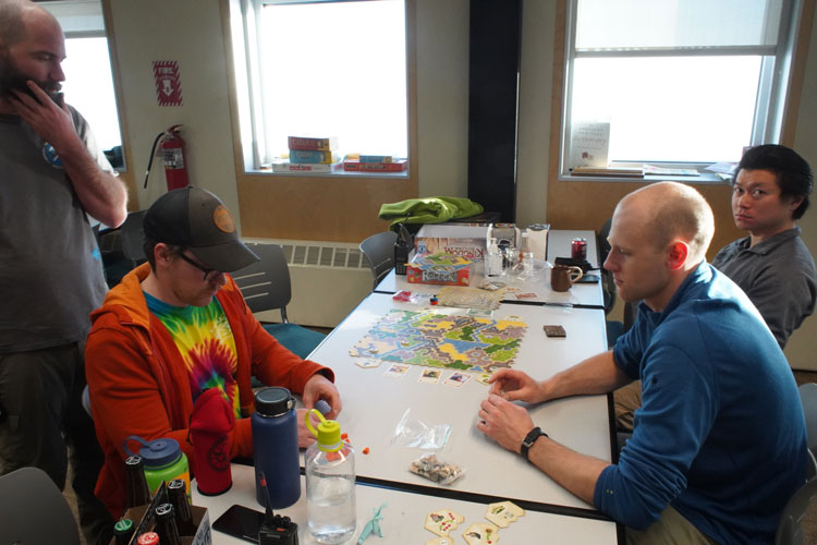 Several people sitting at a table, playing a boardgame