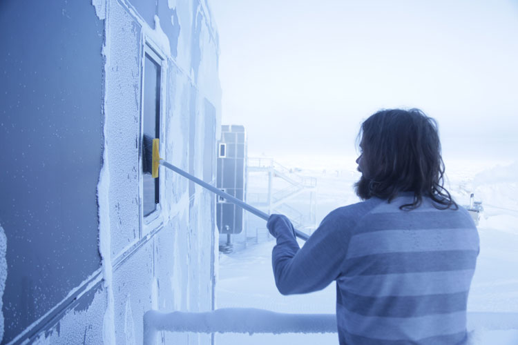 IceCube winterover Christian sweeping snow off window