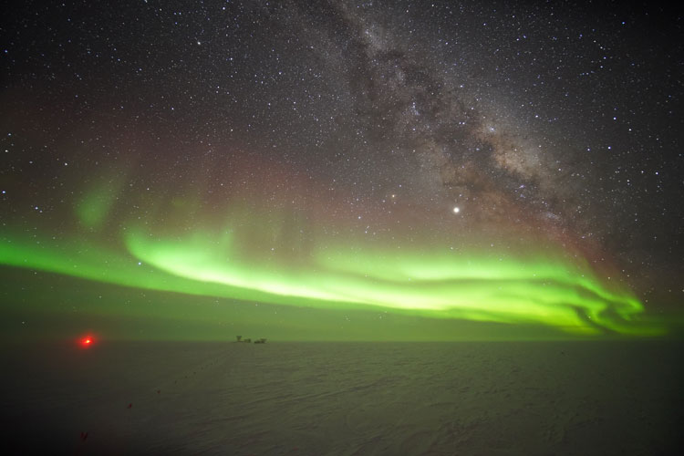 Bright auroras over horizon, with Milky Way clearly above