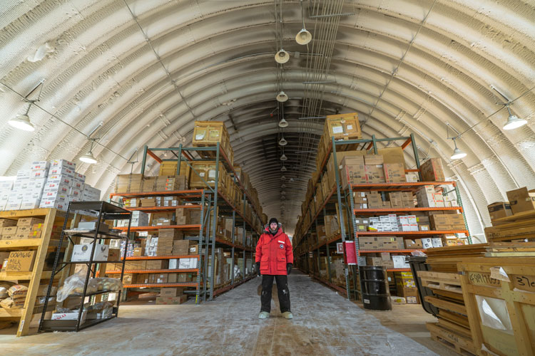 Long view of aisle and person standing in forefront, inside food storage facility at South Pole