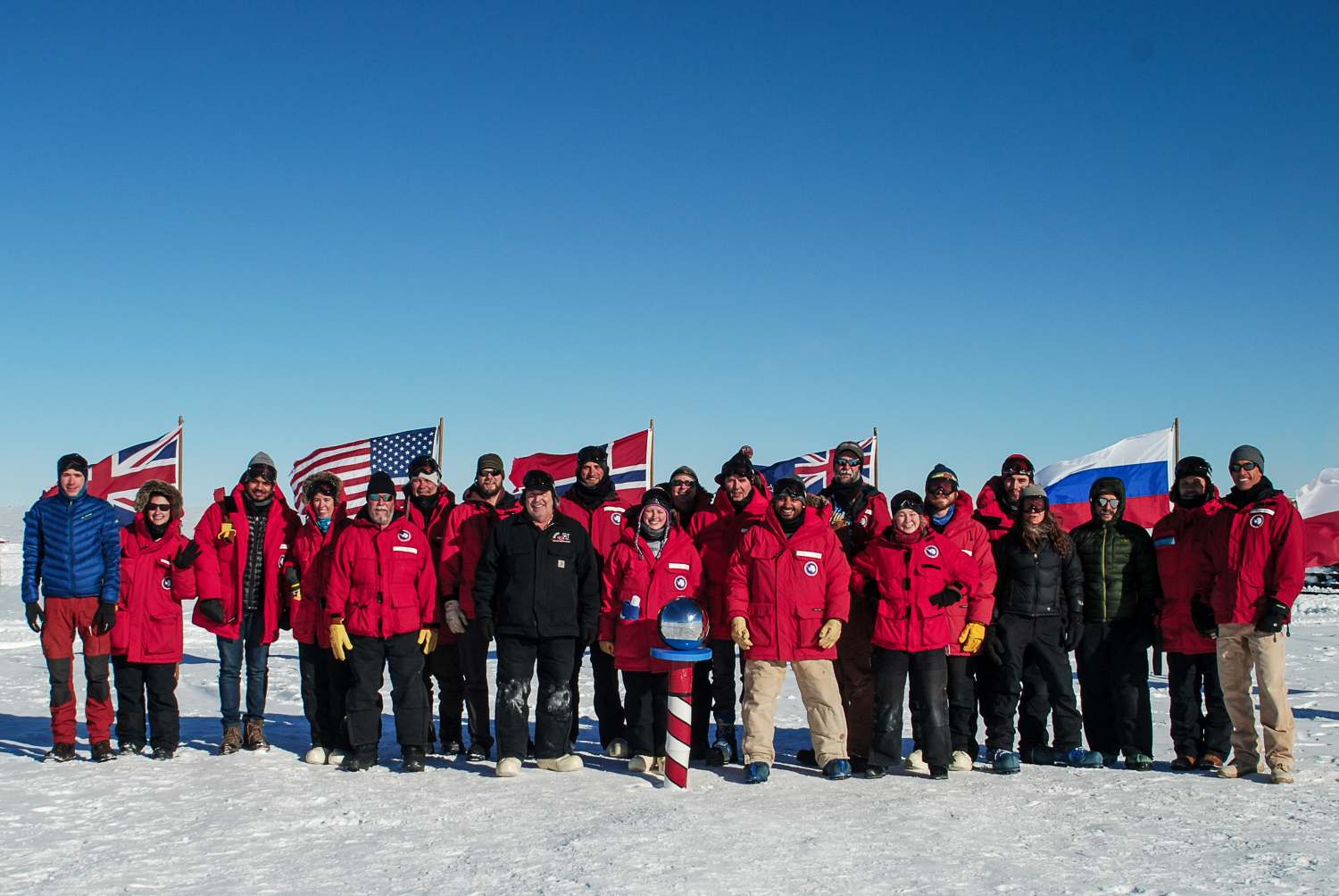 Group photo of 20-plus people at ceremonial pole
