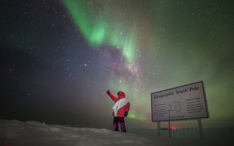 Martin at South Pole sign, with towel, hitchhiking