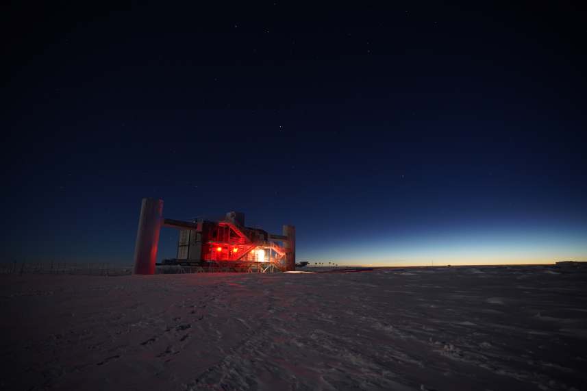 IceCube Lab lit up in red, with last of sunlight at horizon