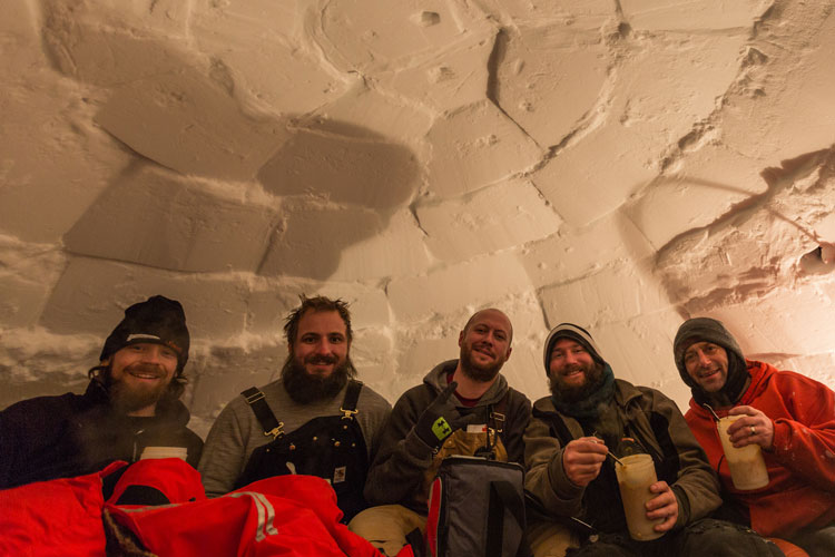 Group enjoying a warm treat inside igloo they built