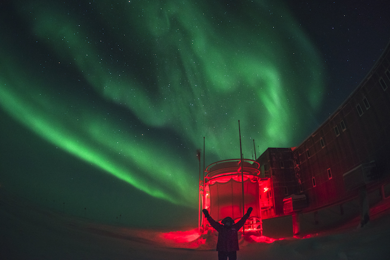 Green aurora over South Pole station bathed in red light