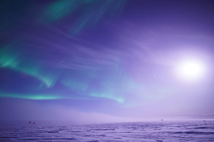 Moon in sky, some wispy auroras visible