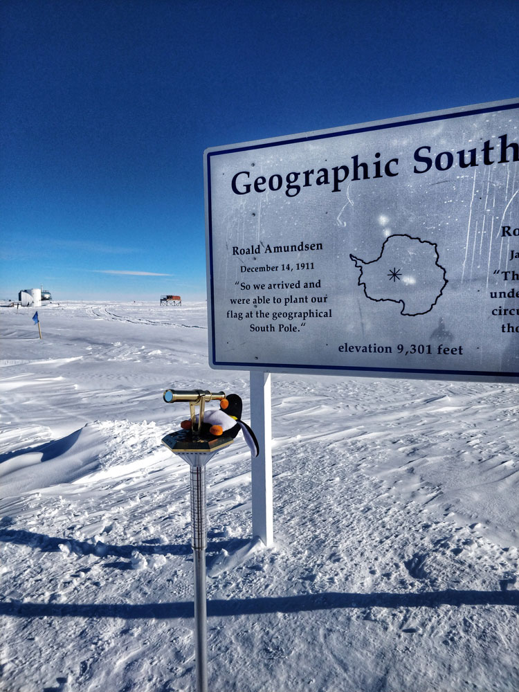 Stuffed animal penguin atop the geographic South Pole marker