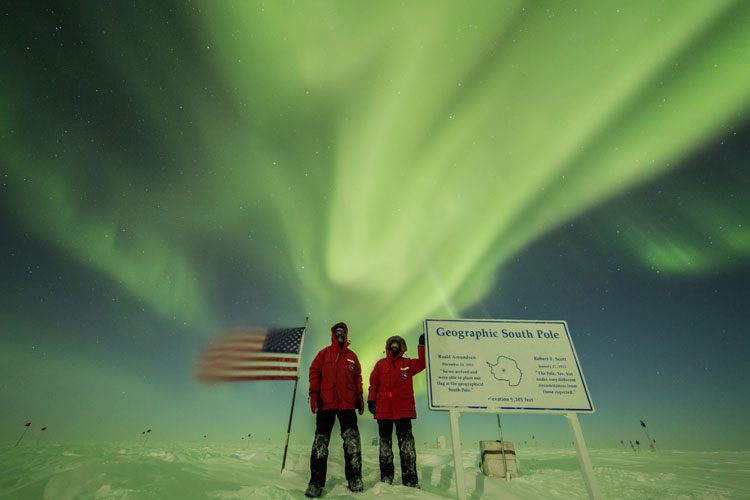 Posing at geographic South Pole with aurora overhead.