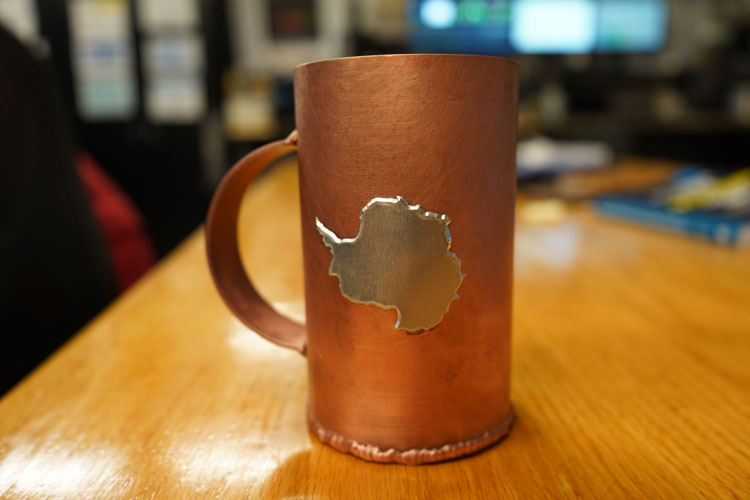 Close-up of handcrafted copper mug with Antarctica shape decoration