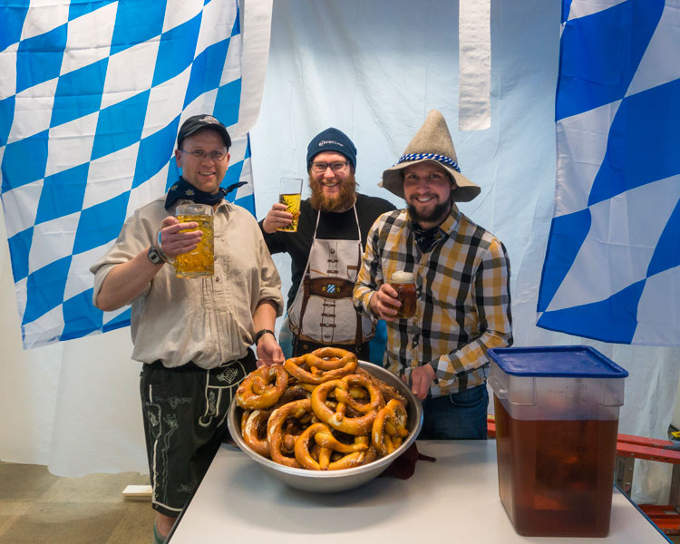 Three winterovers standing around large bowl of pretzels