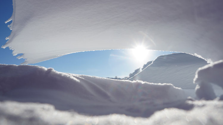Sun seen through snow formations on ground