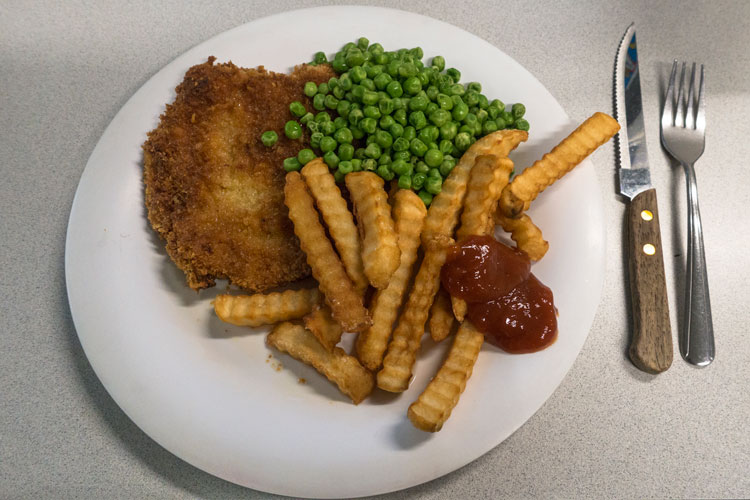 Plate of schnitzel, french fries, and peas.