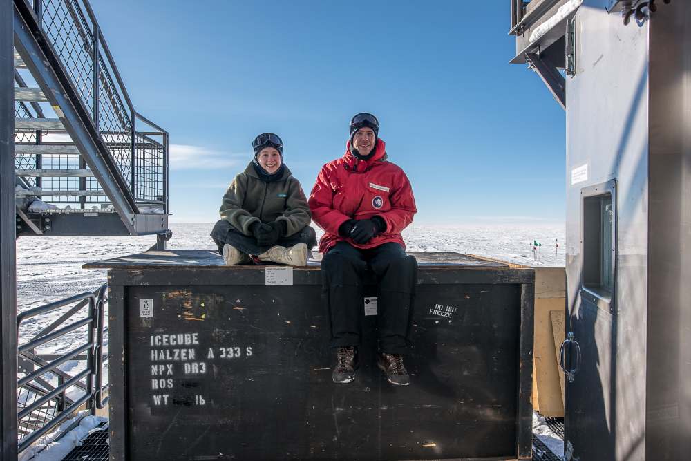 Two people sitting atop a large cargo crate.