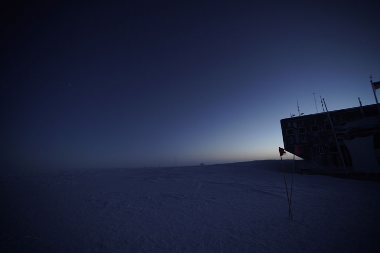 Darkened sky, a bit of light from behind South Pole station