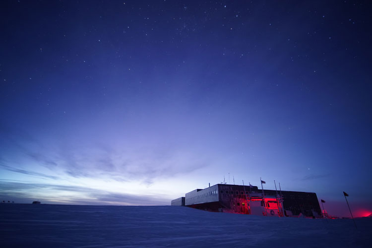 South Pole station lit from behind at twilight