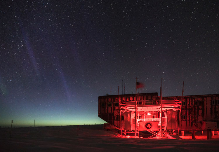 South Pole station under starry sky with glow along horizon