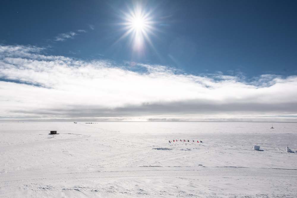 snow storm approaching along horizon at south pole under sunny sky