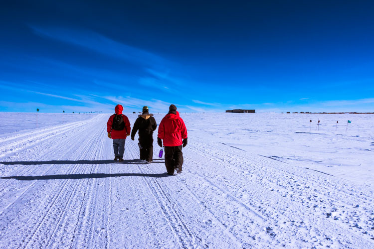 Three people walking back to South Pole station