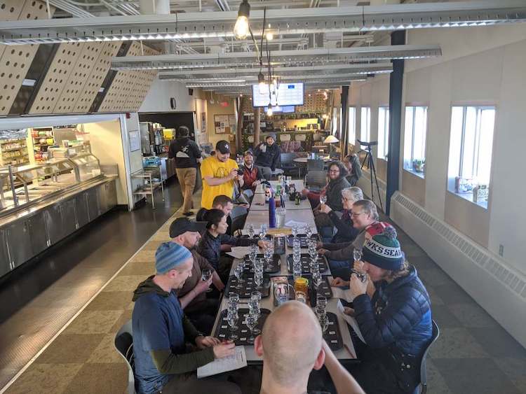 End view of long table with people seated for tasting test