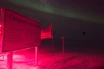 Catching a great photo of the Geographic South Pole point with auroras in the background. 